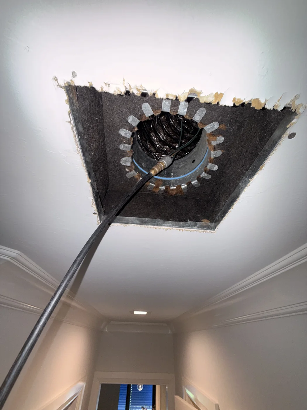Flexible service line positioned through an open ceiling duct connection