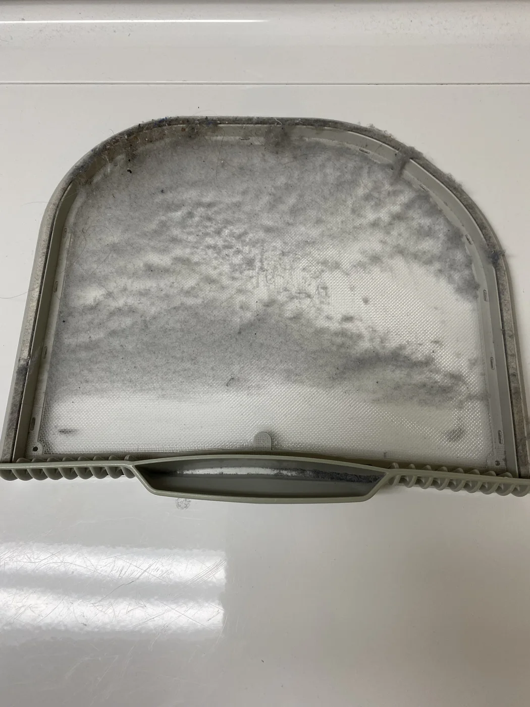 Dryer lint screen with lint covering much of the mesh